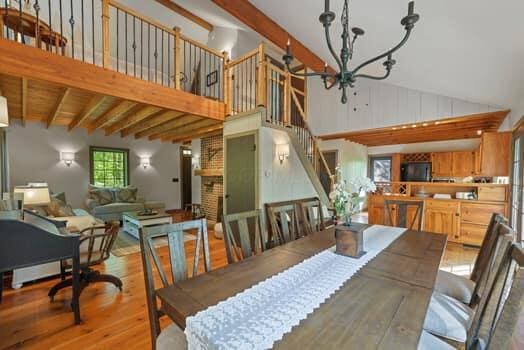 dining area featuring beam ceiling, light hardwood / wood-style flooring, high vaulted ceiling, and a notable chandelier