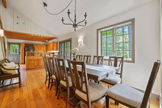 dining room with high vaulted ceiling, light hardwood / wood-style floors, and a notable chandelier