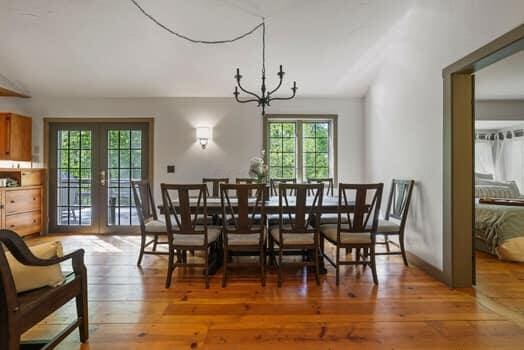 dining space featuring lofted ceiling, an inviting chandelier, wood-type flooring, and french doors