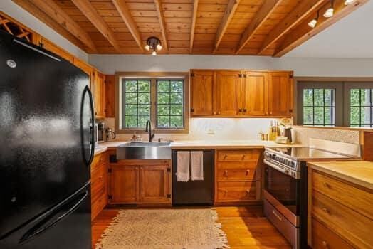 kitchen with sink, wooden ceiling, light hardwood / wood-style flooring, beamed ceiling, and black appliances