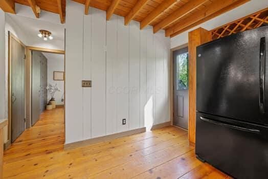 kitchen with beam ceiling, black fridge, wood ceiling, and light wood-type flooring