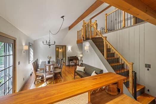 dining space featuring beamed ceiling, hardwood / wood-style flooring, high vaulted ceiling, and a notable chandelier