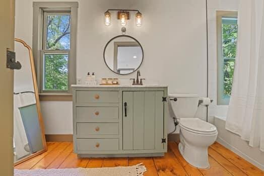 full bathroom featuring shower / bath combination with curtain, vanity, toilet, and a wealth of natural light