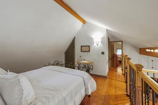 bedroom featuring vaulted ceiling with beams and light hardwood / wood-style flooring