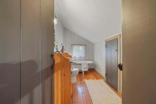 bathroom with toilet, wood-type flooring, vaulted ceiling, and walk in shower