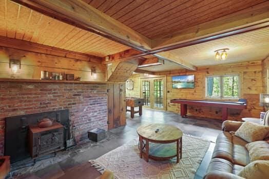 living room featuring a wood stove, wood walls, beamed ceiling, and wood ceiling