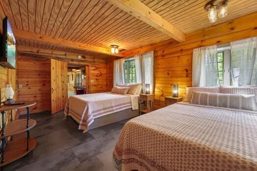 bedroom featuring beamed ceiling, multiple windows, wooden walls, and wood ceiling