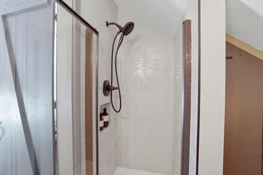 bathroom featuring tiled shower and vaulted ceiling