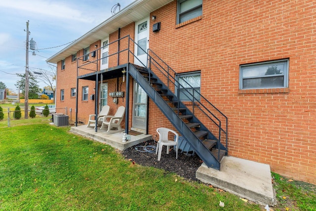 rear view of property with a yard, a patio, and central air condition unit