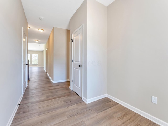 hall with baseboards and light wood-style flooring
