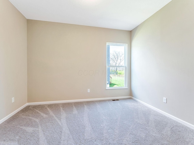 empty room with baseboards, visible vents, and carpet
