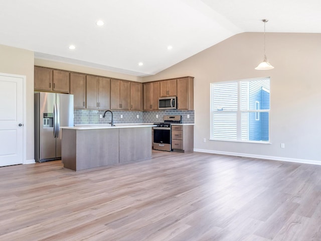 kitchen with stainless steel appliances, a kitchen island with sink, lofted ceiling, decorative backsplash, and light countertops