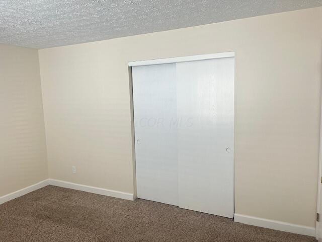 unfurnished bedroom featuring carpet, a textured ceiling, and a closet