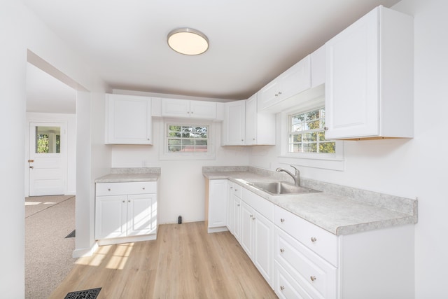 kitchen featuring white cabinetry, sink, and light hardwood / wood-style flooring