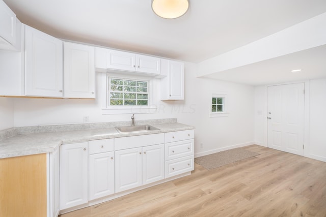 kitchen with light hardwood / wood-style floors, white cabinetry, a healthy amount of sunlight, and sink