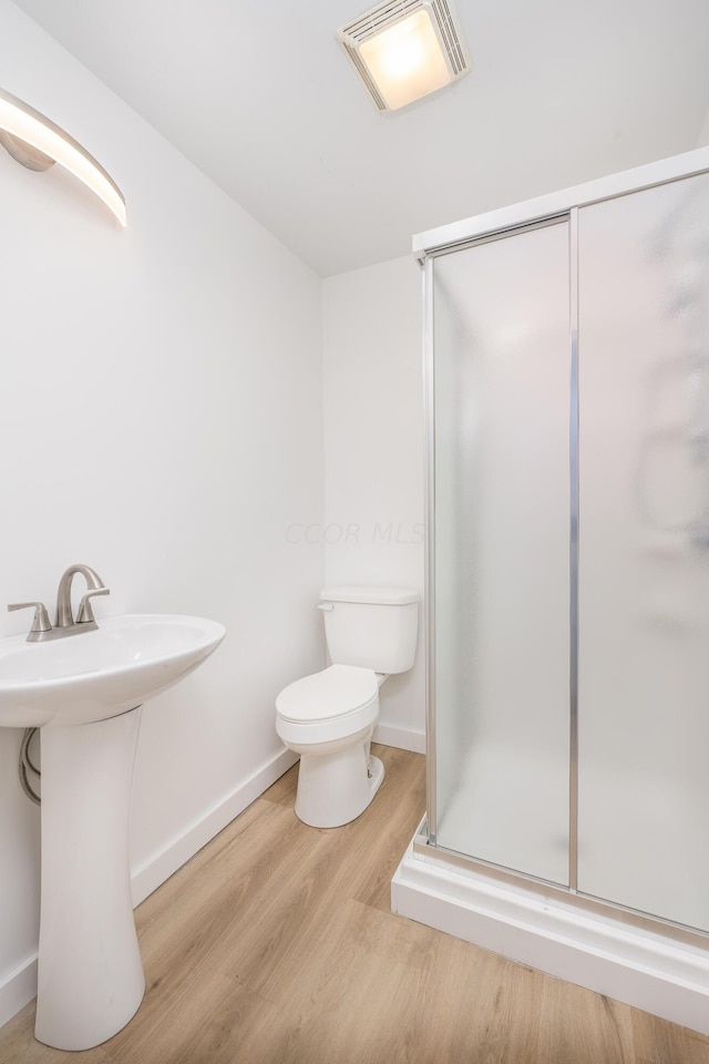 bathroom featuring hardwood / wood-style floors, an enclosed shower, and toilet