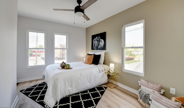 bedroom featuring multiple windows, ceiling fan, and light wood-type flooring