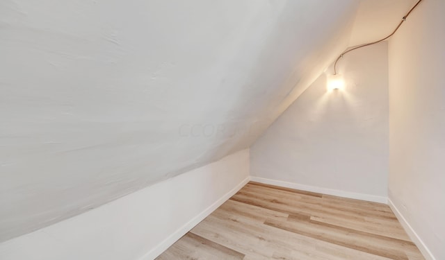 additional living space featuring light wood-type flooring and lofted ceiling