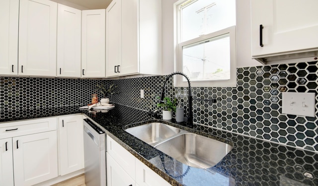 kitchen with dishwasher, white cabinets, sink, decorative backsplash, and dark stone countertops