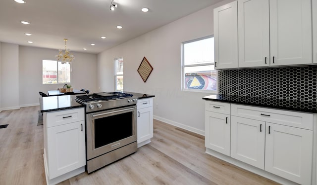 kitchen featuring decorative backsplash, light wood-type flooring, stainless steel gas range, an inviting chandelier, and white cabinetry