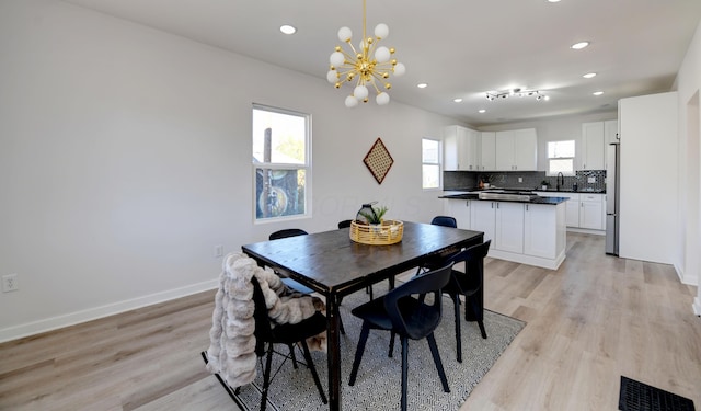 dining room featuring a chandelier, sink, and light hardwood / wood-style flooring