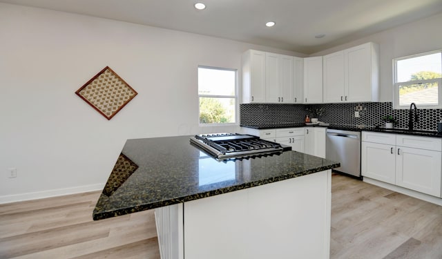 kitchen featuring sink, dark stone countertops, a healthy amount of sunlight, white cabinetry, and stainless steel appliances