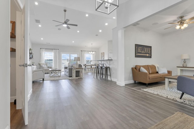 living room with a high ceiling, ceiling fan, and dark wood-type flooring