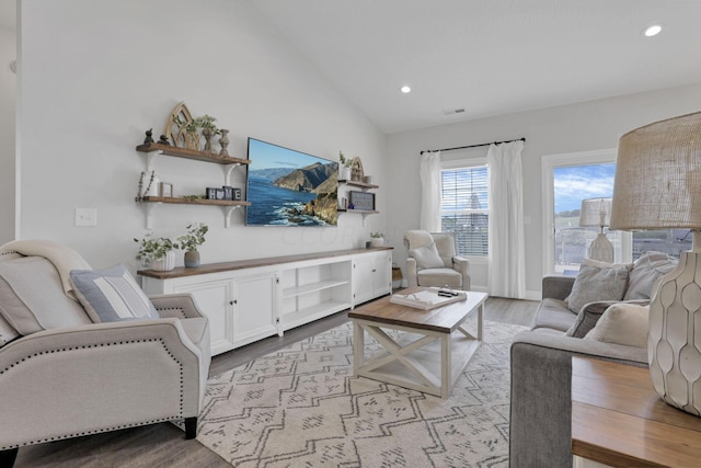 living room with high vaulted ceiling and light hardwood / wood-style flooring