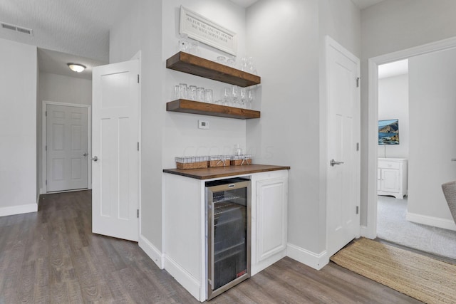 bar with dark hardwood / wood-style flooring and beverage cooler