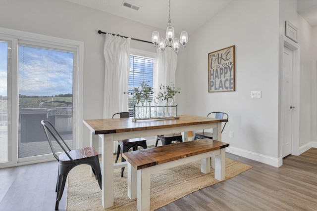 dining space with light hardwood / wood-style flooring, lofted ceiling, and a notable chandelier