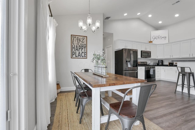 dining space with high vaulted ceiling, a chandelier, and hardwood / wood-style flooring