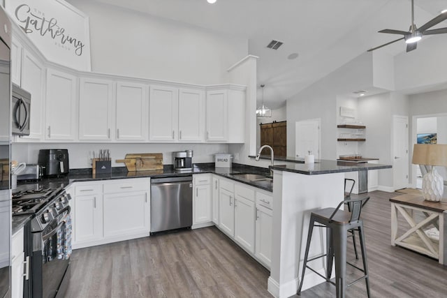 kitchen featuring kitchen peninsula, appliances with stainless steel finishes, white cabinetry, and sink