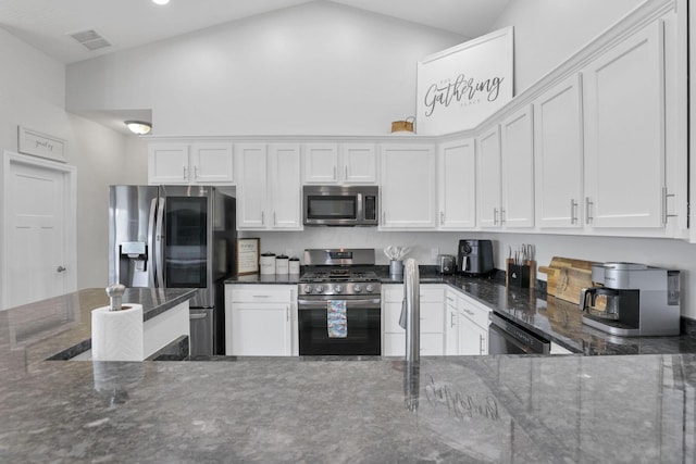 kitchen featuring dark stone counters, white cabinetry, high vaulted ceiling, and stainless steel appliances