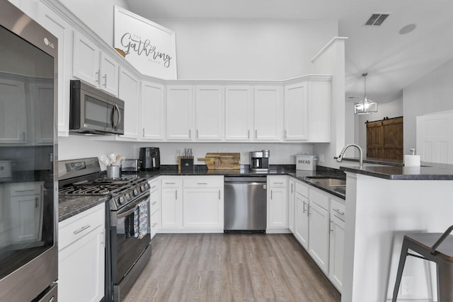 kitchen with black appliances, pendant lighting, white cabinets, and kitchen peninsula