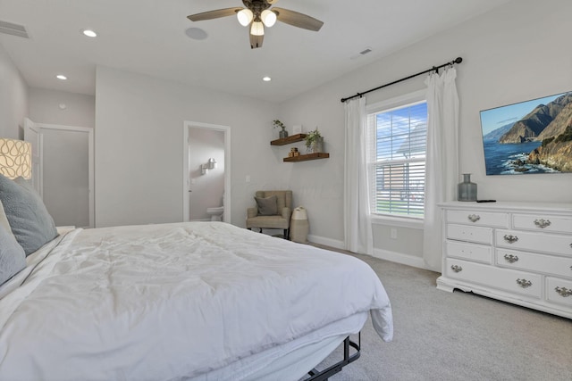 bedroom featuring light colored carpet, ensuite bath, and ceiling fan