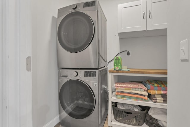 washroom featuring cabinets and stacked washer and dryer