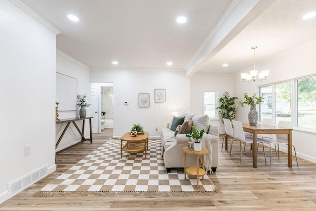 living room with ornamental molding, a wealth of natural light, a notable chandelier, and light hardwood / wood-style floors