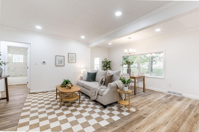 living room featuring crown molding, a chandelier, and light wood-type flooring