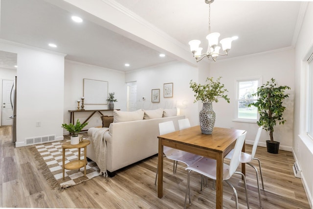 dining area featuring ornamental molding, a notable chandelier, and light hardwood / wood-style flooring