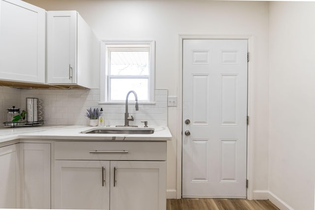 kitchen featuring tasteful backsplash, white cabinetry, and sink