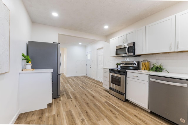 kitchen with white cabinetry, stainless steel appliances, and tasteful backsplash