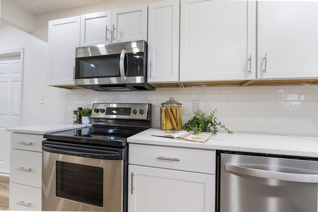 kitchen featuring tasteful backsplash, white cabinetry, appliances with stainless steel finishes, and light stone counters