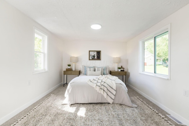 bedroom with light carpet and a textured ceiling