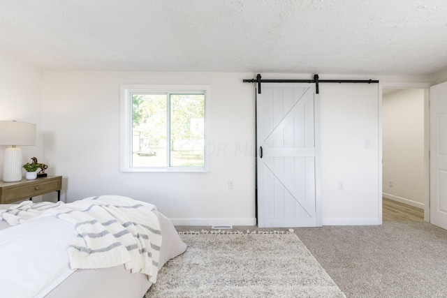 bedroom featuring carpet flooring, a barn door, and a textured ceiling