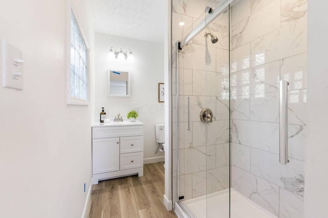 bathroom featuring toilet, an enclosed shower, a textured ceiling, vanity, and hardwood / wood-style floors