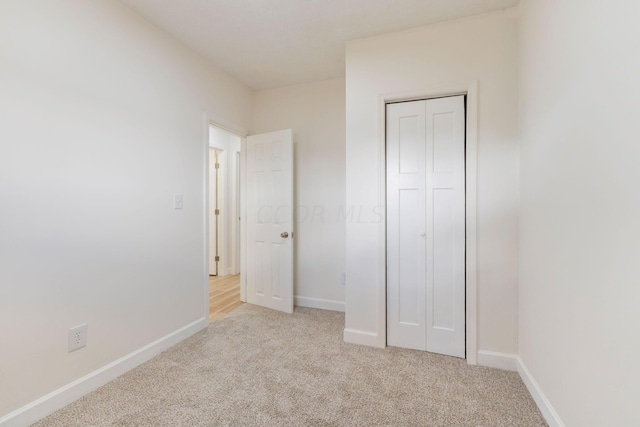 unfurnished bedroom featuring light colored carpet and a closet