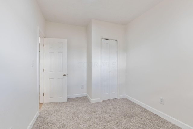 unfurnished bedroom featuring light colored carpet and a closet