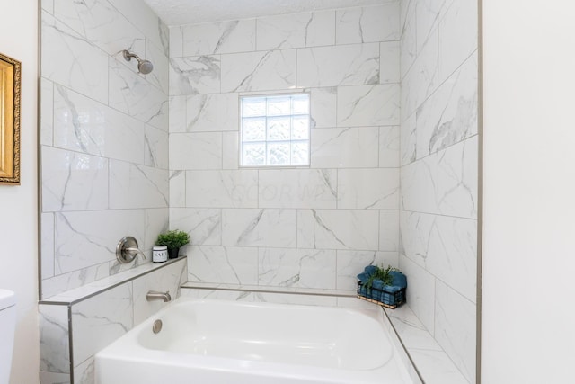 bathroom with tiled shower / bath combo and toilet