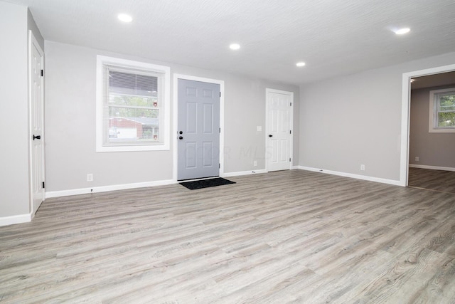 spare room with a textured ceiling, light hardwood / wood-style flooring, and plenty of natural light