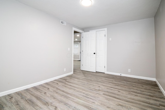 unfurnished bedroom with a closet, light hardwood / wood-style floors, and a textured ceiling